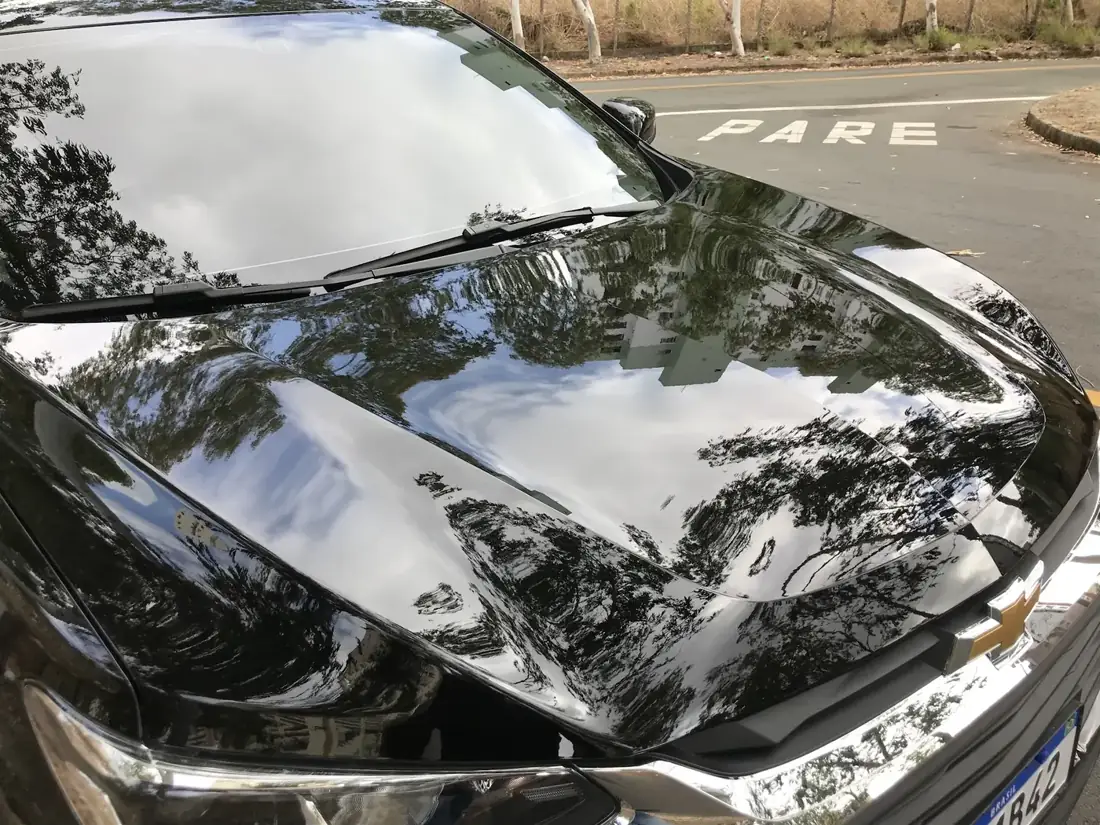 Reflexo de árvores no capô preto polido